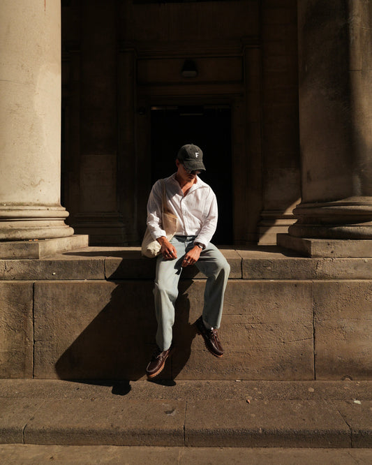 Forrest wearing the Fereday Crochet F Cap, walking through Bristol in a crisp white shirt, light denim jeans, and brown loafers.